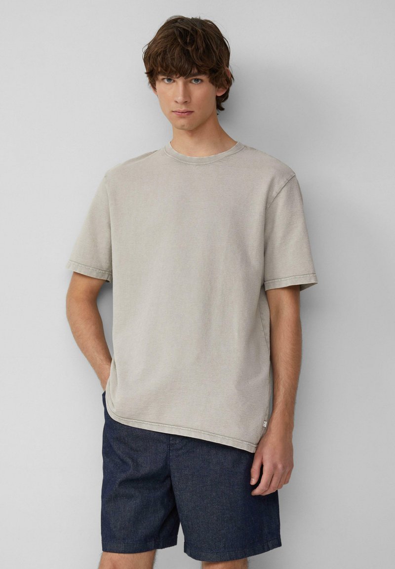 Jasnoszara bawełniana koszulka z krótkim rękawem i okrągłym dekoltem, w połączeniu z ciemnoniebieskimi denimowymi szortami. Prosty i luźny krój.