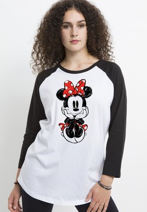 T-shirt bianco con maniche raglan nere, caratterizzato da un fiocco a pois rossi e un'illustrazione di un personaggio dei cartoni animati sul davanti. Tessuto morbido.