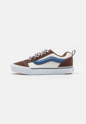 Sneaker in suede marrone e tela crema con striscia laterale blu, suola bianca e lacci a scacchi. Presenta un tassello sul tallone.