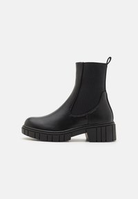 Svart ankelboot med en slät läderytt och elastiska sidpaneler, samt en grov gummisula, med en dragflik bak för enkel påtagning.