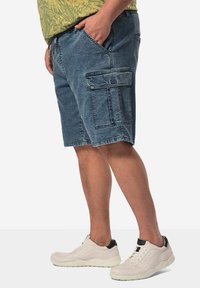 Denim cargo shorts i blekt blått med flera fickor; matchade med vita sneakers med svarta accenter och strukturerade sulor.