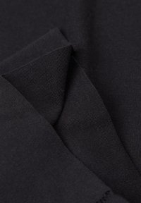 Close-up van gevouwen zwarte stof met fijne gebreide textuur en gelaagde randen.