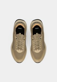 Μπεζ αθλητικά παπούτσια από δίχτυ και συνθετικό υλικό με κλείσιμο με κορδόνια, τονικούς τόνους και μαύρη καουτσούκ σόλα. Το όνομα της μάρκας "BOSS" στις εσωτερικές σόλες.