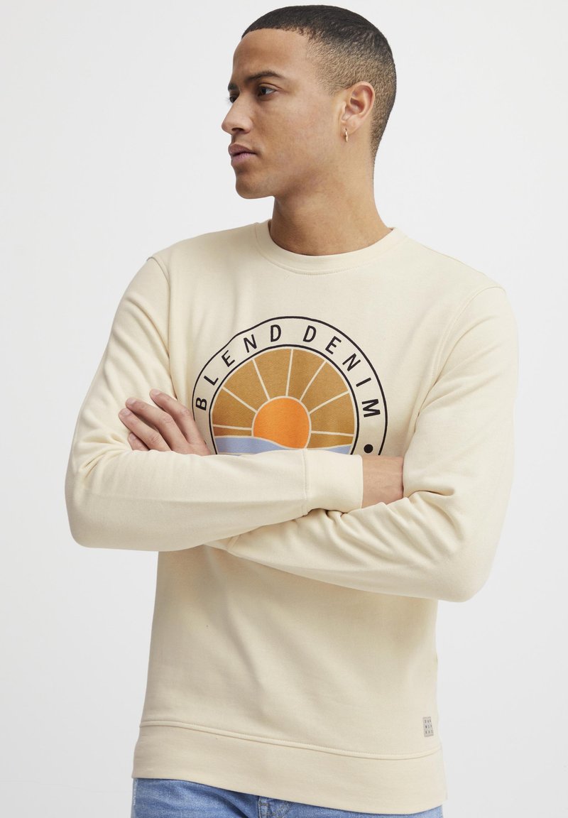Beige sweatshirt van een katoenmix, met een ronde graphic van een zonmotief in oranje, blauw en zwart. Ribgebreide mouwen en zoom.