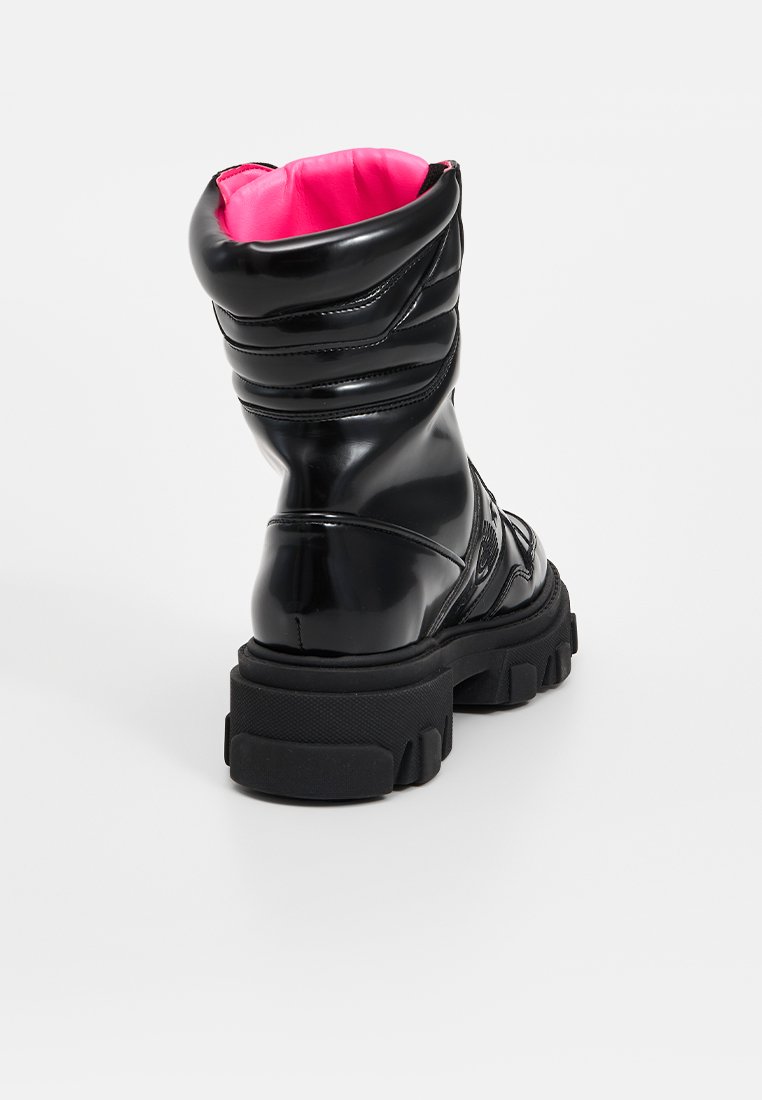 Czarne lakierowane botki z gumową podeszwą, charakteryzujące się masywnym obcasem, wyściełanym kostką i jaskraworóżowym wykończeniem. Gładka tekstura, nowoczesny design.