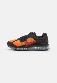 Zapato deportivo negro con una parte superior de malla en naranja y rojo, que cuenta con una suela de amortiguación de aire visible y acentos texturizados en la parte trasera.