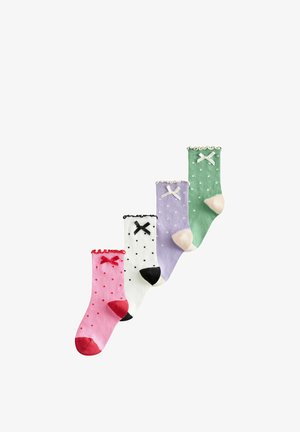 Quatre chaussettes colorées pour enfants avec des pois et des nœuds, en rose, blanc, violet et vert, disposées en diagonale sur un fond blanc.