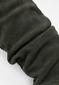 Vihreä mokkakangas, jossa on pehmeä tekstuuri ja hieman kiiltävä pinta, esittelee taitoksia ja rypytyksiä, mikä korostaa sen joustavuutta ja sileää pintaa.