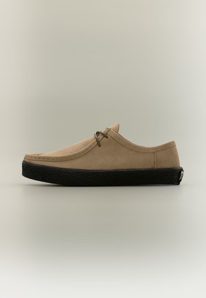 Chaussure décontractée en daim beige avec semelle noire texturée, lacets et coutures simples, vue de profil sur fond uni.