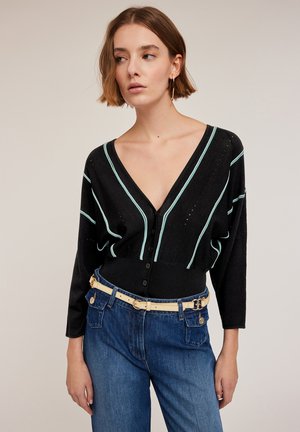 Black V-neck cardigan with turquoise stripes, long sleeves, and button closure. Worn with high-waisted blue jeans and a beige belt.