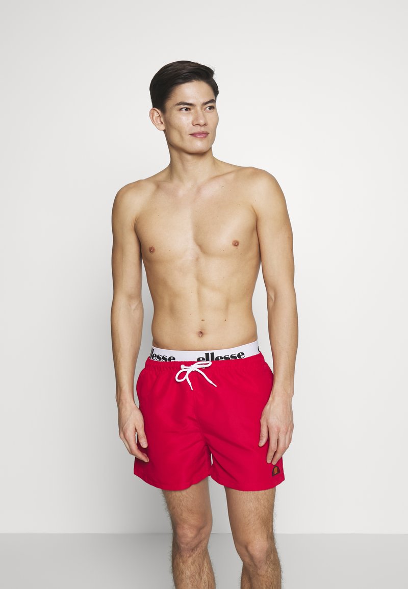 Rote Badeshorts aus schnelltrocknendem Material, mit einem weißen elastischen Bund mit schwarzem Branding und einem Kordelzug.