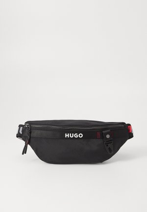Juodas audinys fanny pack su užtrauktuku, turintis baltą "HUGO" logotipą, raudonus akcentus ir reguliuojamą dirželį. Lygi tekstūra; kompaktiškas dizainas.