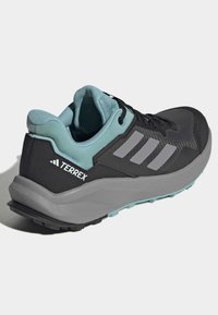 Chaussure de sport noire avec des accents gris et aqua, tige en mesh, col rembourré et semelle texturée pour une meilleure adhérence. Présente le logo à trois bandes.