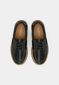 Schwarze Lederschuhe mit abgerundeter Spitze, Schnürdesign und kontrastierendem beigem Nähen; verfügen über eine strukturierte Sohle und eine markierte Innensohle.