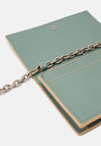 Portafoglio in pelle verde con tracolla a catena, dotato di chiusura a scatto e multiple fessure per carte interne. Superficie testurizzata con accenti beige.