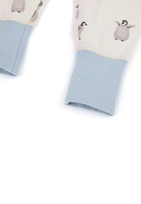 Bomulds pyjamas top med lyseblå manchetter og cremefarvet krop med pingvintryk i nuancer af grå og sort. Blød, glat tekstur.