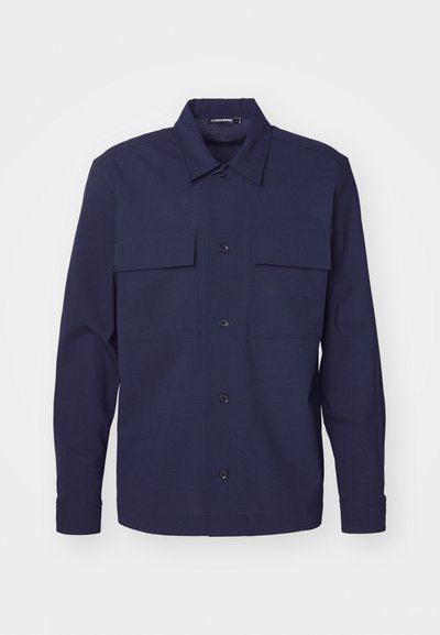 Mørkeblå skjorte med knapper, to brystlommer, lange ærmer og klassisk krave. Fremstillet af et glat stof med en struktureret design.