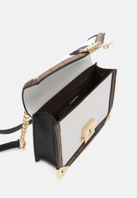 Strukturovaná kabelka ze černé kůže a bílého textilu, se zlatými kovovými doplňky a texturovaným hnědým akcentem, s prostorným interiérem.