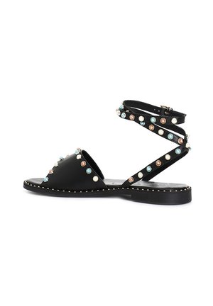 Sandal in pelle nera con punta aperta, fascetta incrociata alla caviglia e borchie decorative colorate. Suola piatta con dettaglio di cuciture a contrasto.