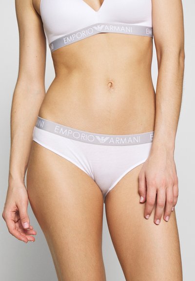 White cotton blend bralette and thong set with a light grey waistband featuring the "Emporio Armani" logo. Smooth texture, minimal design.