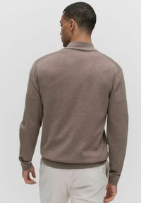 Bruine gebreide trui met lange mouwen en een geribde zoom, met een eenvoudig ontwerp en een zachte textuur. Geen zichtbare patronen of hardware accenten.