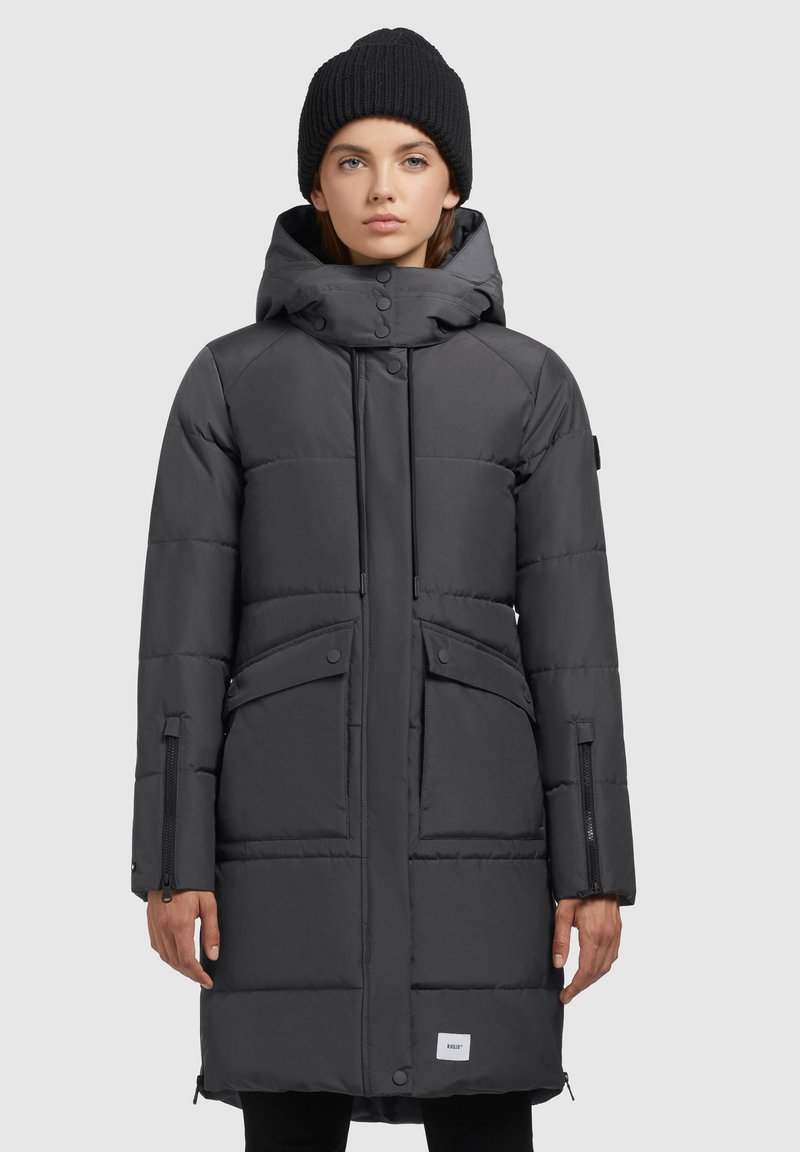 Padded dark gray parka with a zip closure, adjustable hood, and two front pockets. Features textured fabric and a branded label at the hem.