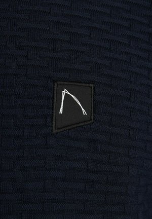 Marine gebreide stof met een gemêleerd patroon, met een zwarte rechthoekige patch met een wit geometrisch ontwerp.