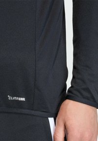 Μαύρο αθλητικό μπλουζάκι με μακρύ μανίκι και λεία υφή. Διαθ έτει το λογότυπο "CLIMACOOL" και εφαρμοστή σχεδίαση. Περιλαμβάνει αντίθετες λευκές λεπτομέρειες.