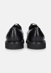 Zwarte leren dresschoenen met een gladde afwerking, ronde neus en dikke zwarte rubberen zool. Voorzien van minimale stiksels en twee trekbanden.
