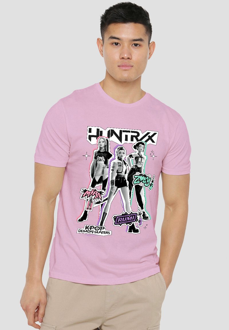 Man wearing a pink T-shirt with three stylized female K-pop characters and text "Kpop Demon Hunters" on front.