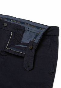 Navigeren katoenen broek in marineblauw met een ritsluiting en knoopsluiting, en contrasterende binnenband. Opvallende stiksels en pocketdetails.