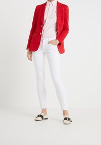 Czerwony dopasowany żakiet, jasnoróżowa koszula w paski, białe legginsy skinny i dwukolorowe mokasyny z teksturowanym wzorem i detalem w postaci klamry.