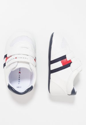 Zapatos de bebé blancos con rayas azul marino y rojas, tiras de velcro y suelas negras, etiquetados como Tommy Hilfiger, talla 17.