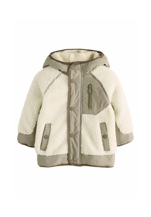 Kermainen shearling- ja nylontakki beigen reunustuksen kanssa. Siinä on huppu, nepparit, kaksi sivutaskua ja vetoketjullinen tasku rintakehällä.
