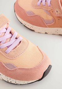 Pinky og ferskenfarvede sneakers med en kombination af suede og tekstilmaterialer. Prikket beige sål, snørebånd foran og kontrastfarvede lavendelfarvede accenter.