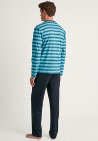 Langemouwen, blauw en turkooise gestreept shirt in combinatie met zwarte broek. De stof lijkt zacht en comfortabel, ideaal voor vrijetijdskleding.