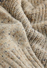 Beige strikket stof med struktureret ribbing, prydet med striber af brun og blå over det hele. Blød tekstur med et varmt udseende.