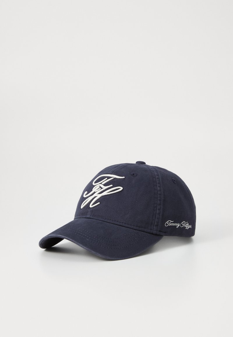 Navy blue baseball cap made of cotton, featuring embroidered initials on the front and brand name on the side in white thread.