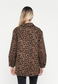 Giacca in stampa leopardata con vestibilità rilassata, polsini con bottoni e colletto. Realizzata in tessuto testurizzato nei toni di marrone e nero.