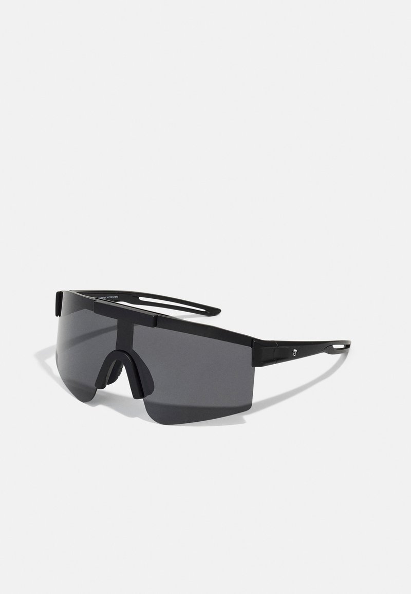 Gafas de sol negras de gran tamaño con un marco de plástico resistente, diseño envolvente y lentes oscuros que cuentan con un puente nasal y acentos laterales mínimos.