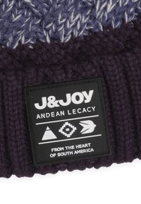 Gebreide beanie in donkerpaars met een textuurpatroon, voorzien van een zwart label met de tekst "J&JOY" en geometrische ontwerpen.