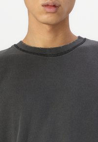 Gray cotton t-shirt with a ribbed crew neckline and visible stitching details, featuring a smooth texture and relaxed fit.