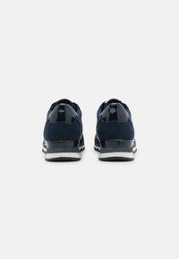 Sneakers blu navy con tomaia in rete e dettagli in pelle verniciata lucida. Presentano una suola intermedia bianca e una suola in gomma testurizzata per una buona aderenza.