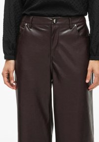 Pantalons en simili cuir bordeaux avec une texture lisse, dotés de poches avant, d'une fermeture à bouton et d'un design à jambes droites.