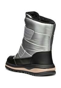 Botas de tobillo aisladas en plata y negro, con parte superior metálica acolchada, correas de Velcro y una suela de goma texturizada con un acento beige.
