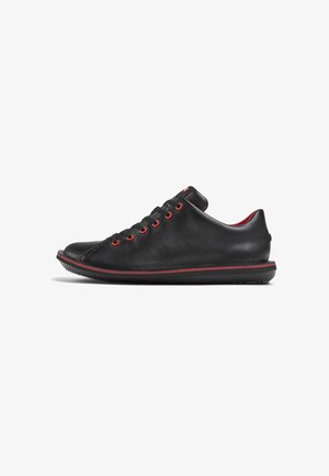Schwarze Leder-Sneaker mit roten Ösen und Akzenten, mit abgerundeter Zehenpartie und strukturiertem Obermaterial, auf einer schwarzen Gummisohle.