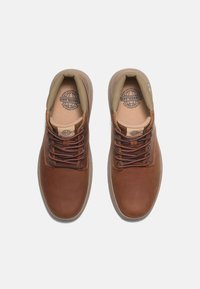 Braune Lederschuhe mit glatter Oberfläche, ausgestattet mit braunen Schnürsenkeln und einem hellen Stofffutter, abgerundeter Zehenpartie und strukturiertem Gummisohlen.