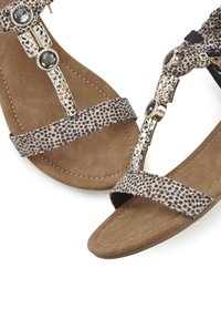 Tiermotiv-Sandalen mit einer weichen, beigen Fußbett, ausgestattet mit dekorativer silberner Hardware und einem Riemendesign für einen sicheren Sitz.
