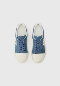 Baskets en denim avec une tige bleu texturé, un bout et une semelle en caoutchouc blanc, et des lacets bleu foncé. Caractéristiques d'un détail logo sur le côté.