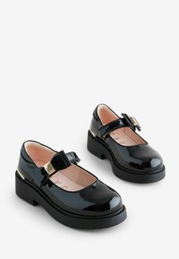 Zwarte gepatineerde leren Mary Jane schoenen met een ronde neus, een bandje over de wreef en een decoratieve strik. Stevige blokhak. Roze voering.